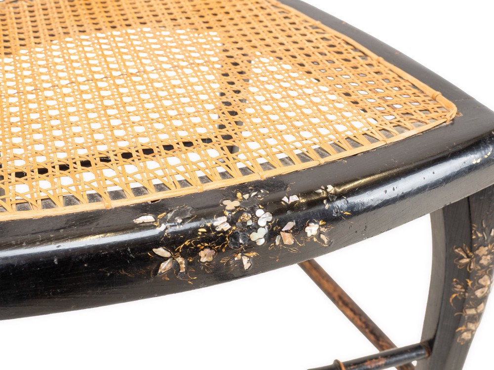 A black japanned papier-mache side chair with mother-of-pearl floral inlay, gold leaf flourishes, a openwork backrest, cabriole front legs, and a woven cane seat. View IX