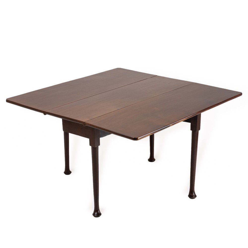 An antique dark walnut drop-leaf gateleg table shown with both extension leaves fully raised and slender turned legs.