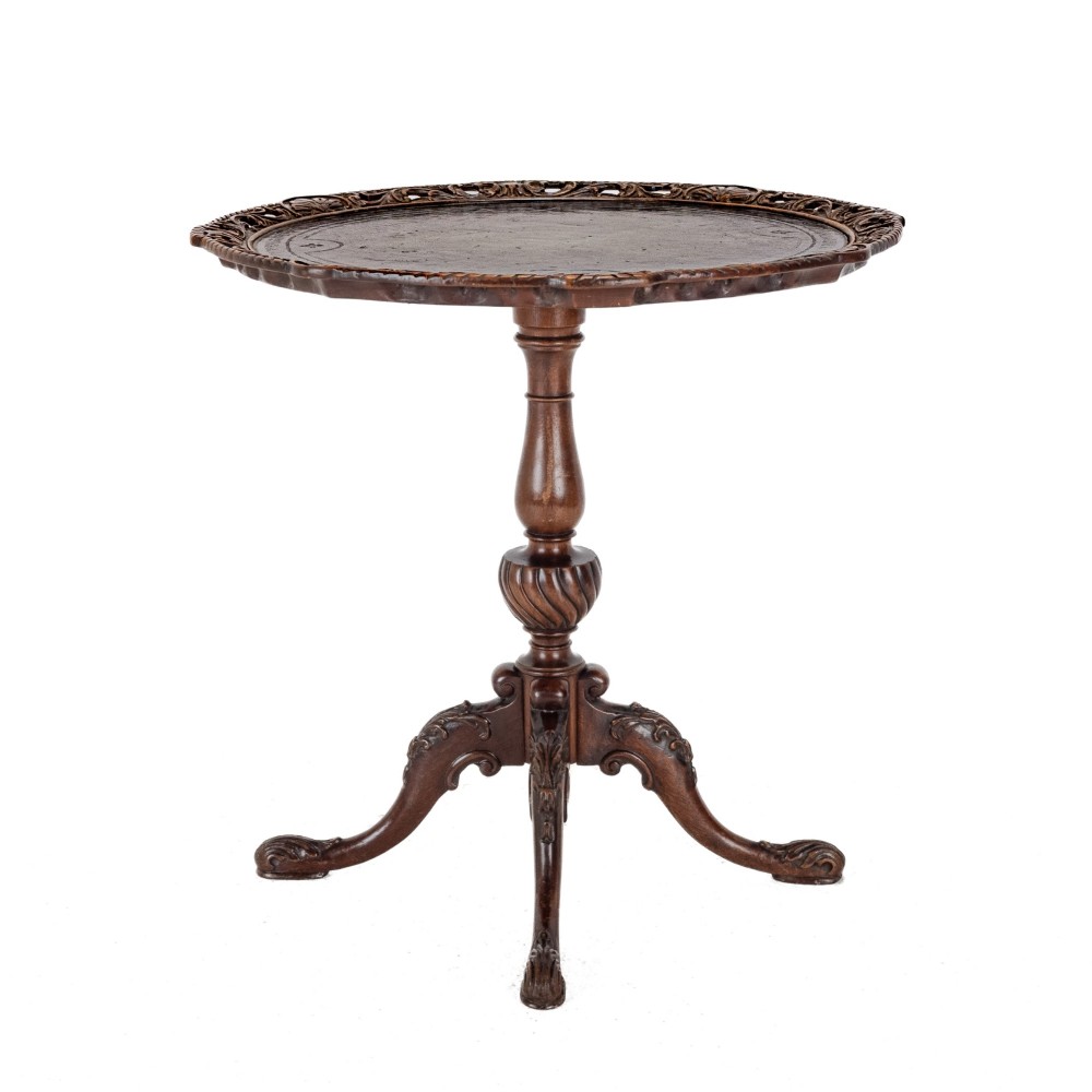 A Chippendale Revival mahogany wine table featuring a green leather top, a piecrust border, a carved central pedestal, and a carved tripod base. View V