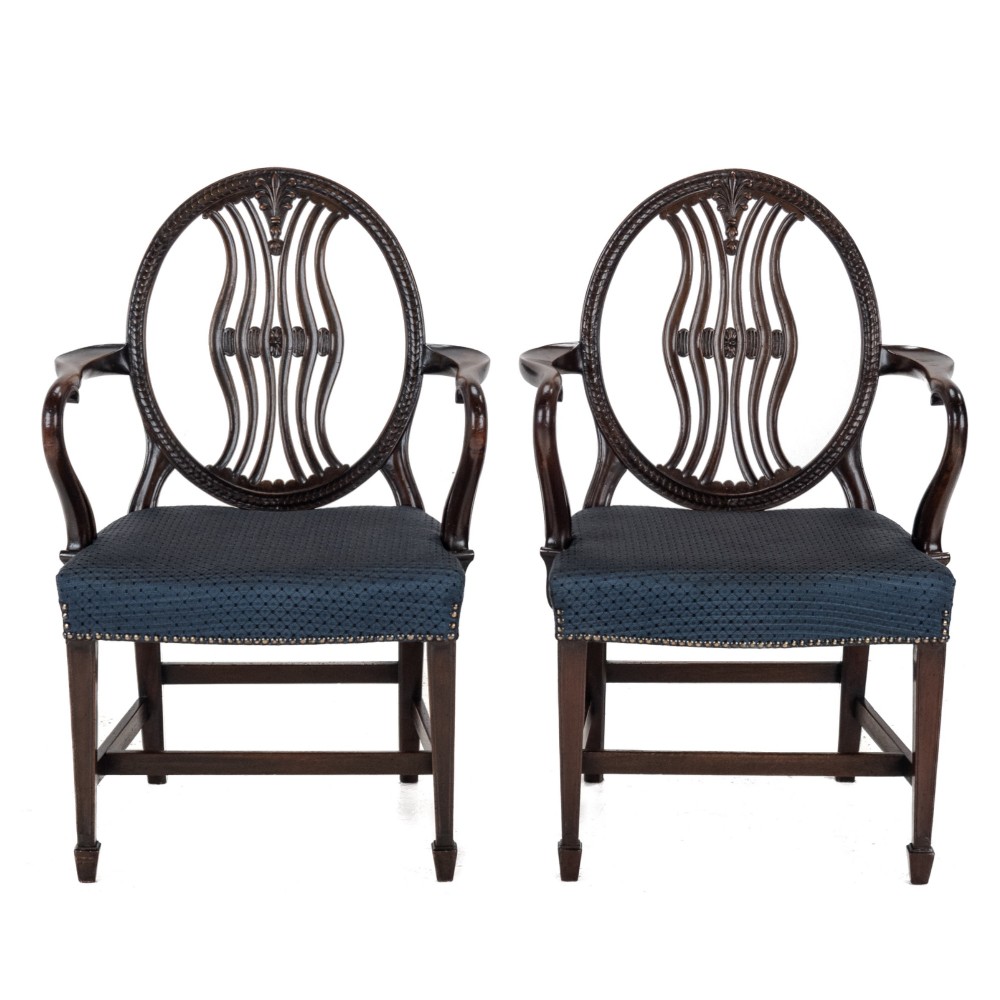 A pair of late 19th-century mahogany Hepplewhite-style carver armchairs featuring carved oval backs and navy blue upholstered seats with brass studding. View II