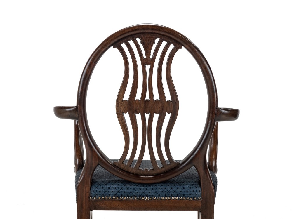 A pair of late 19th-century mahogany Hepplewhite-style carver armchairs featuring carved oval backs and navy blue upholstered seats with brass studding. View V