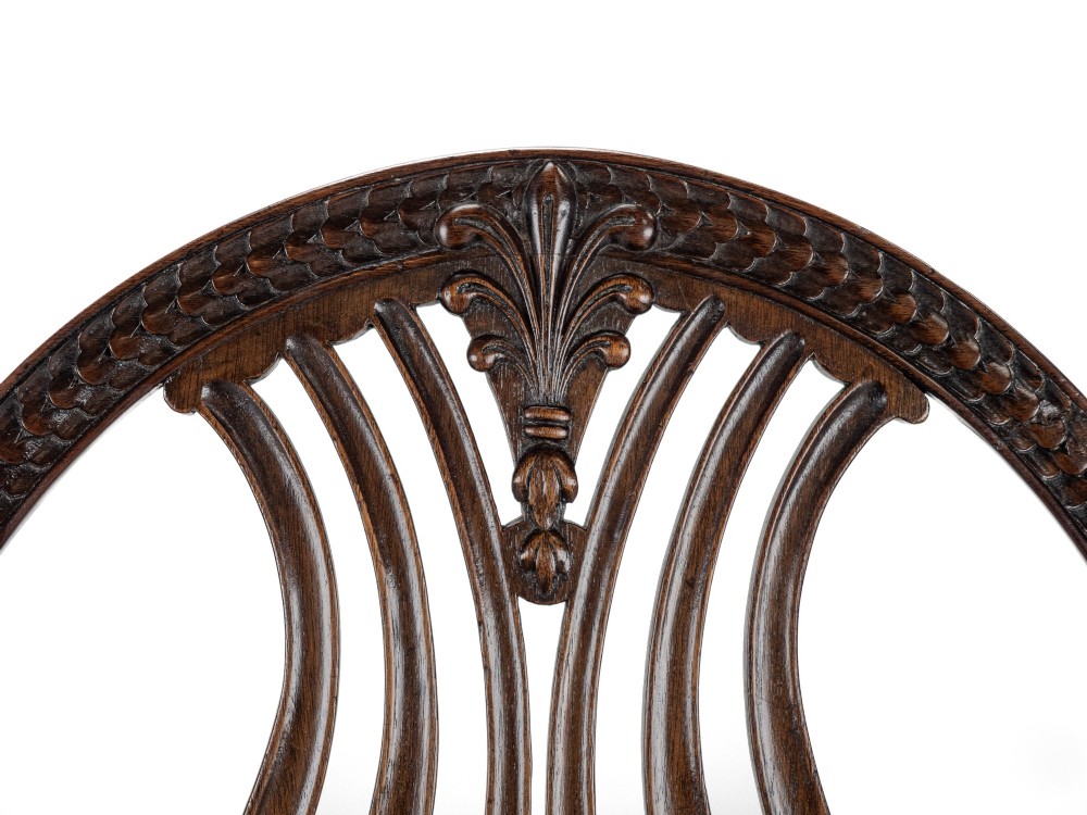 A pair of late 19th-century mahogany Hepplewhite-style carver armchairs featuring carved oval backs and navy blue upholstered seats with brass studding. View X