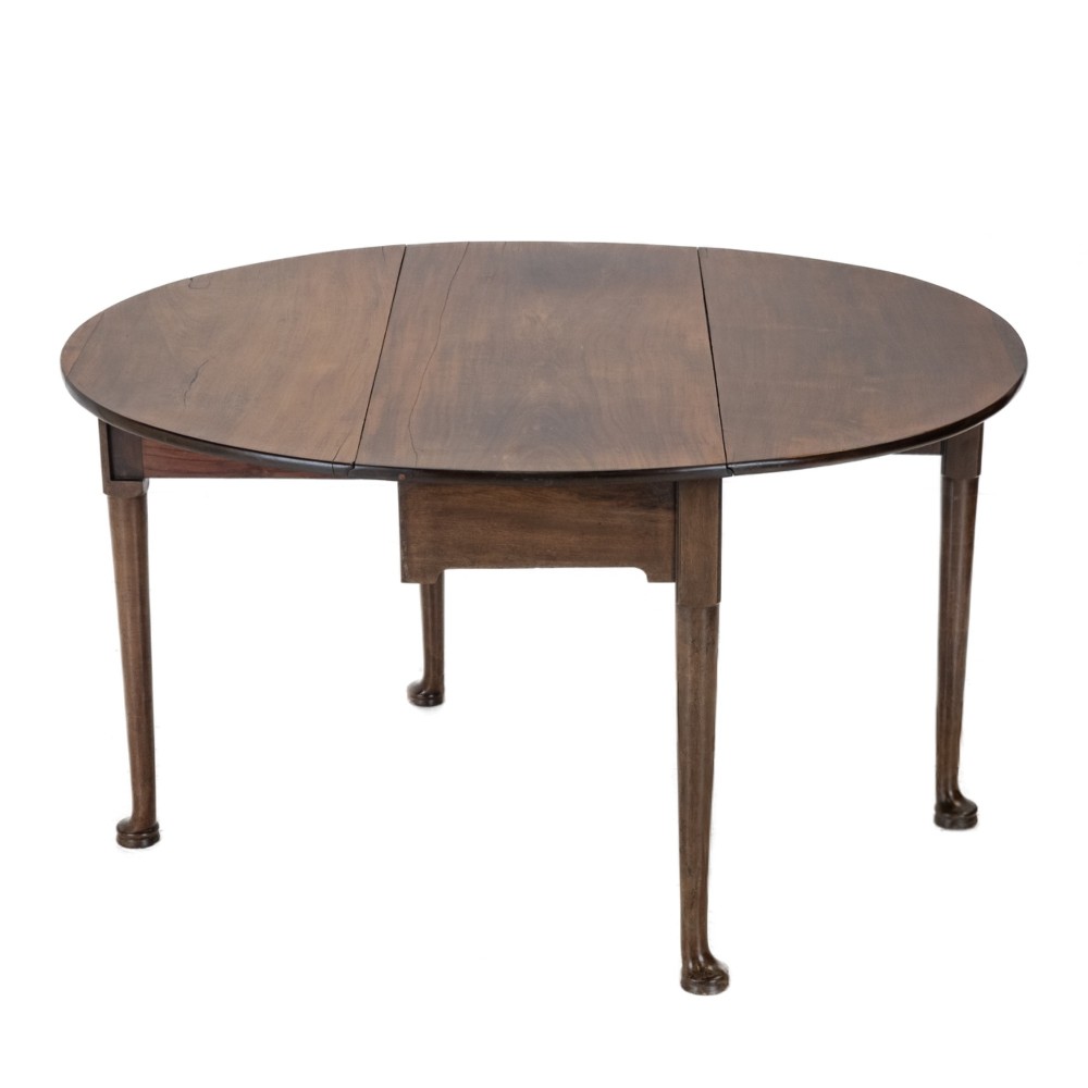 A George II mid-18th century dark mahogany oval drop-leaf table with slender legs ending in pad feet.