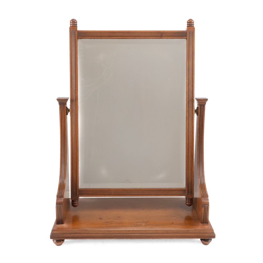 A late 19th-century mahogany table top dressing mirror featuring fluted upright columns, finials, a bevelled rectangular mirror plate, and a moulded wooden base on bun feet. View II