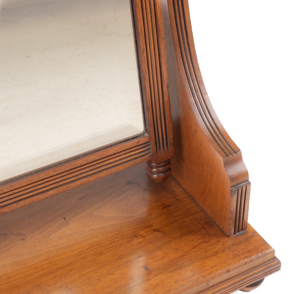 A late 19th-century mahogany table top dressing mirror featuring fluted upright columns, finials, a bevelled rectangular mirror plate, and a moulded wooden base on bun feet. View V