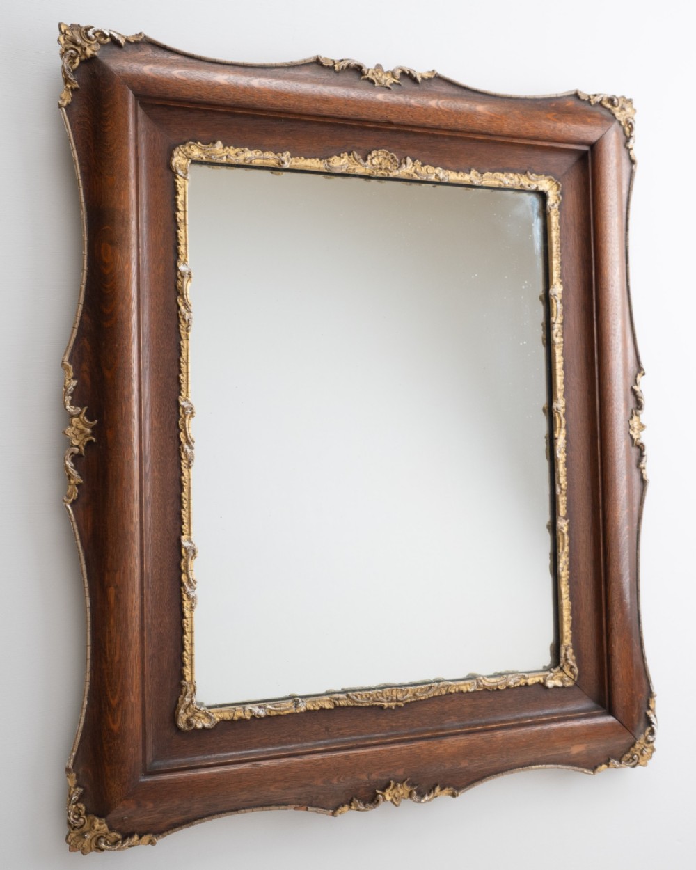 A rectangular dark oak wall mirror featuring a moulded timber frame with gilded gesso accents at the corners, outer edges, and inner sight edge. View II
