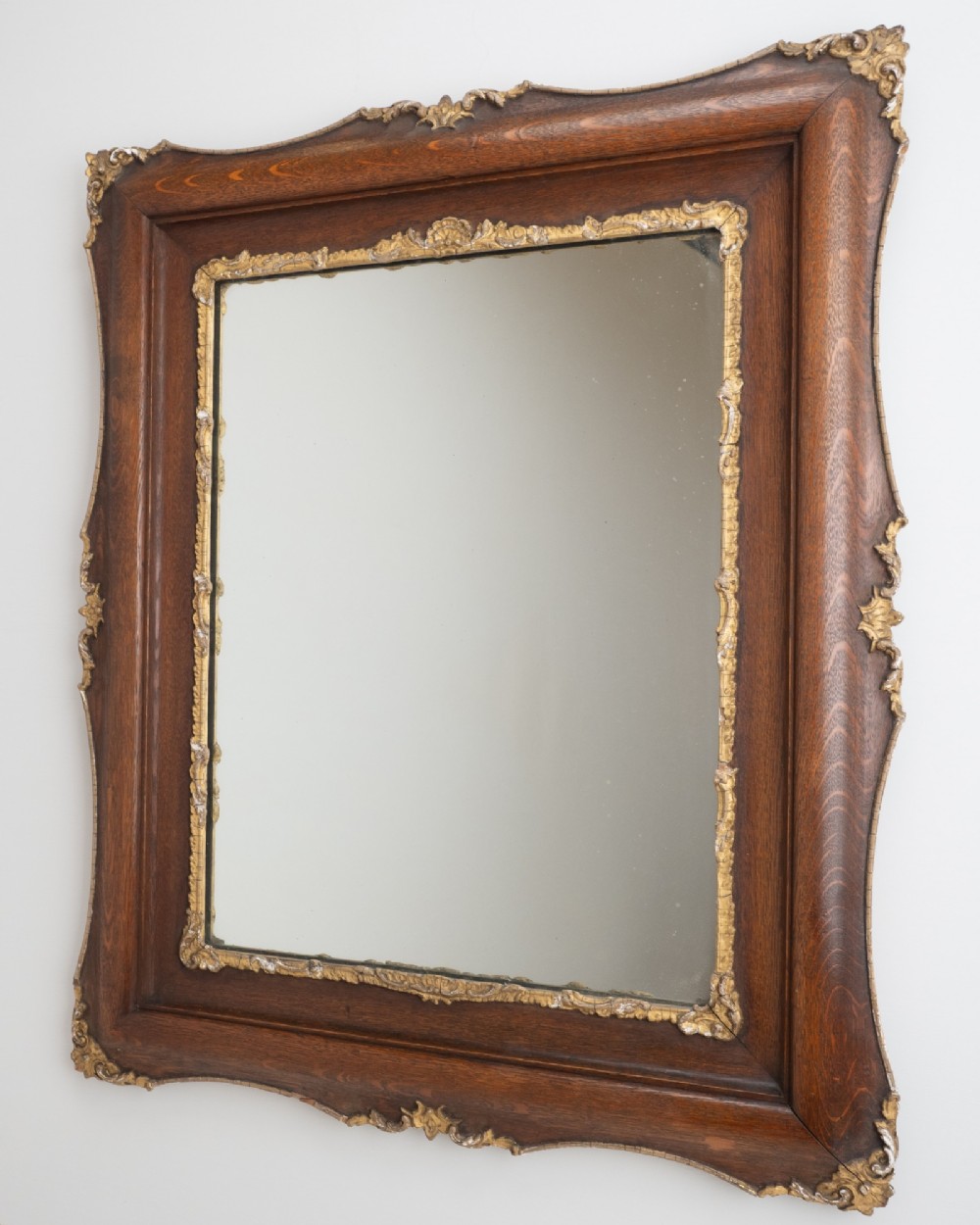 A rectangular dark oak wall mirror featuring a moulded timber frame with gilded gesso accents at the corners, outer edges, and inner sight edge. View III