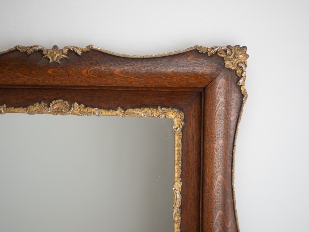 A rectangular dark oak wall mirror featuring a moulded timber frame with gilded gesso accents at the corners, outer edges, and inner sight edge. View IV