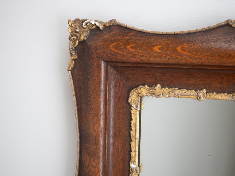 A rectangular dark oak wall mirror featuring a moulded timber frame with gilded gesso accents at the corners, outer edges, and inner sight edge. View VI