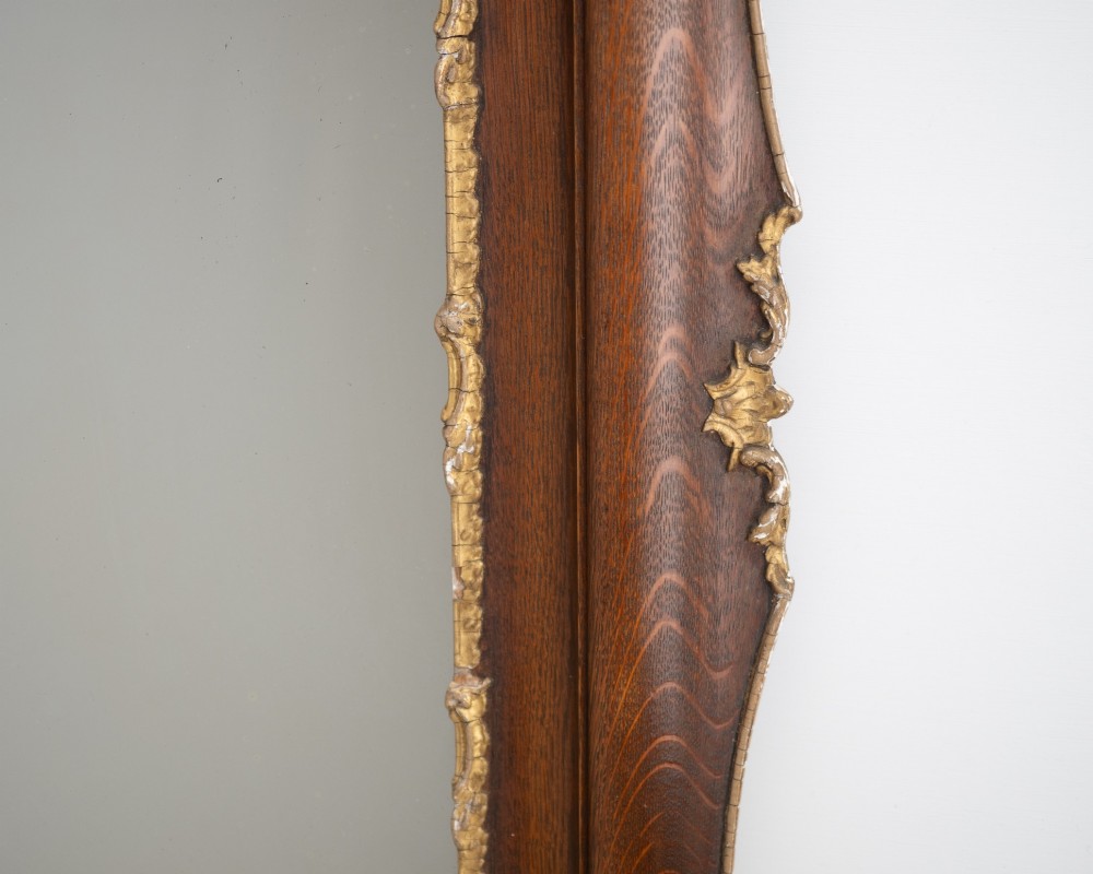 A rectangular dark oak wall mirror featuring a moulded timber frame with gilded gesso accents at the corners, outer edges, and inner sight edge. View VIII