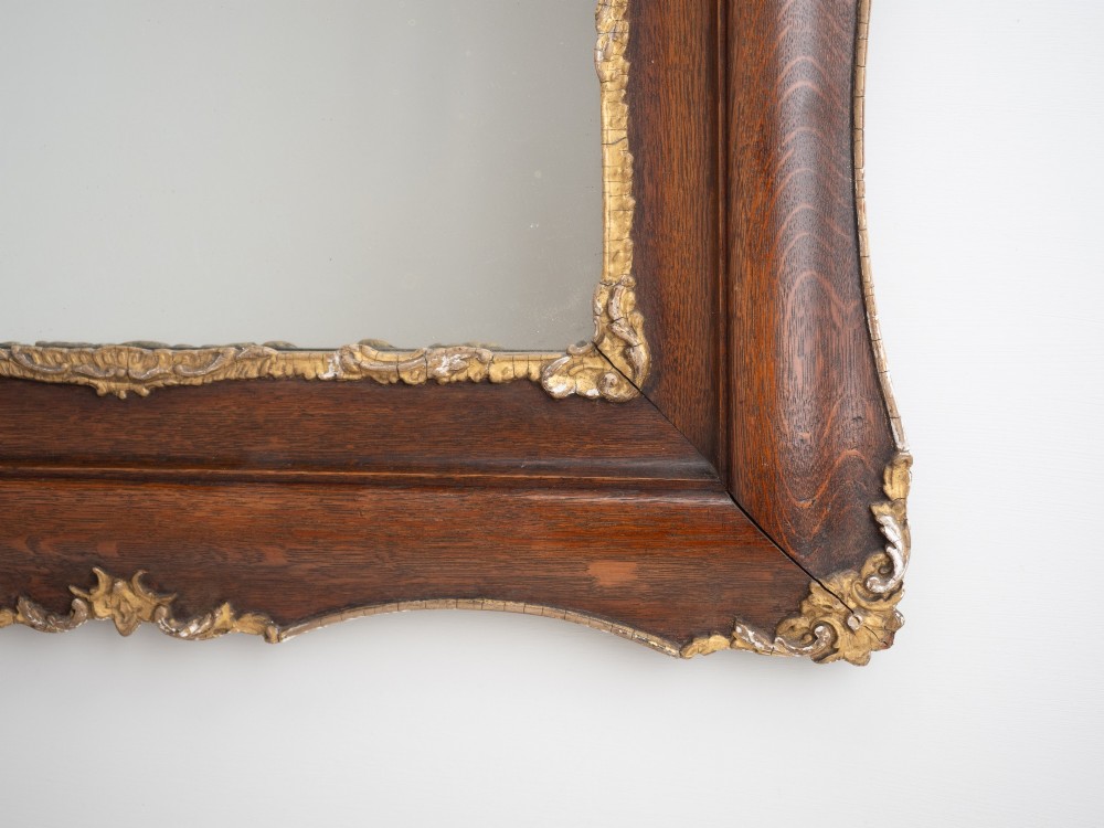 A rectangular dark oak wall mirror featuring a moulded timber frame with gilded gesso accents at the corners, outer edges, and inner sight edge. View IX