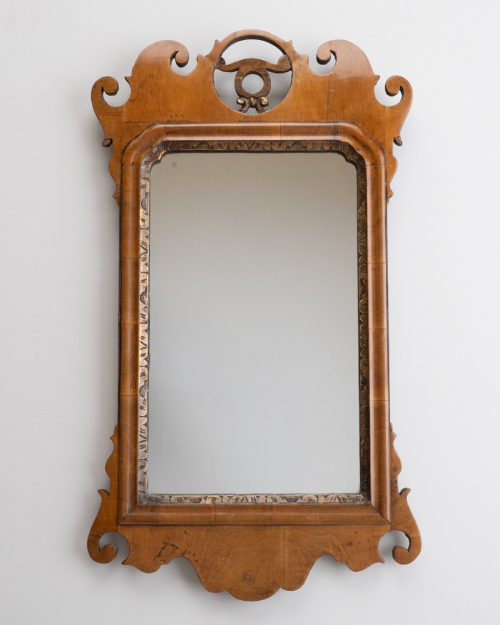 An 18th-century sycamore fretwork wall mirror featuring scrolled cresting with an openwork crest motif, a moulded rectangular frame, and an inner carved gilt slip.