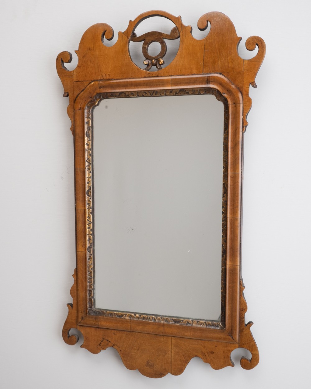 An 18th-century sycamore fretwork wall mirror featuring scrolled cresting with an openwork crest motif, a moulded rectangular frame, and an inner carved gilt slip. View II