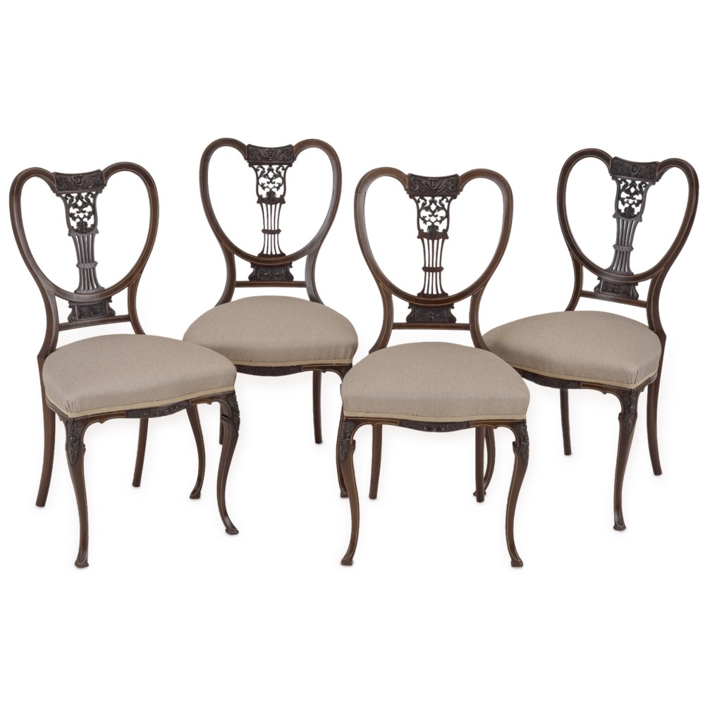 A set of four Sheraton Revival mahogany salon chairs featuring openwork heart-shaped backs with intricate carved splats, neutral upholstered seats, and cabriole front legs.