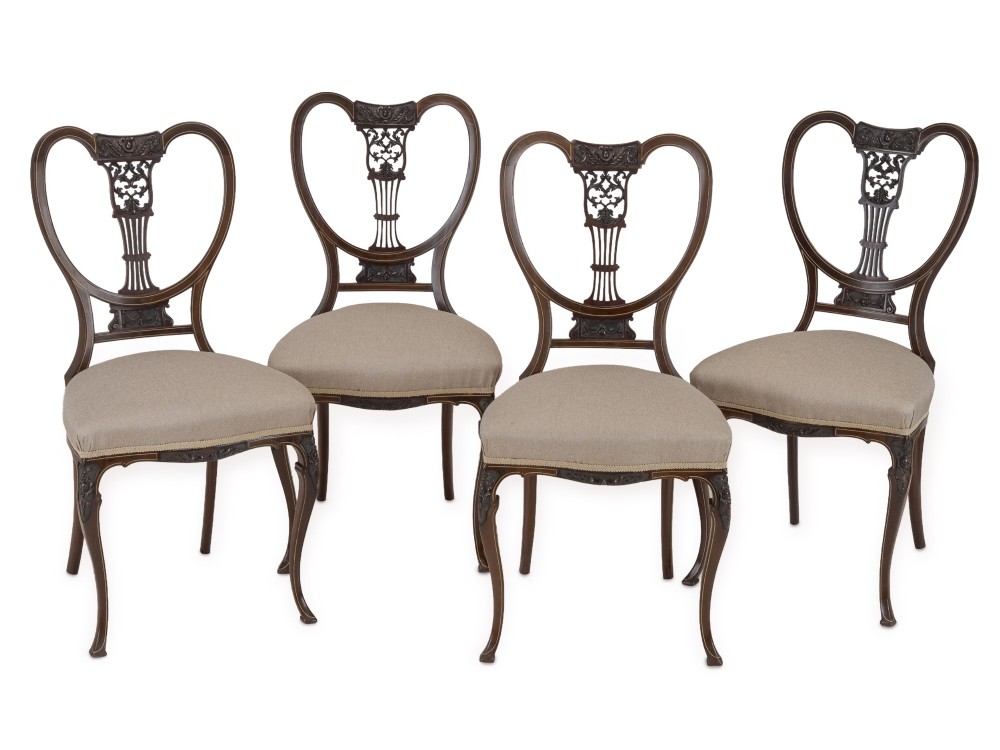 A set of four Sheraton Revival mahogany salon chairs featuring openwork heart-shaped backs with intricate carved splats, neutral upholstered seats, and cabriole front legs. View V