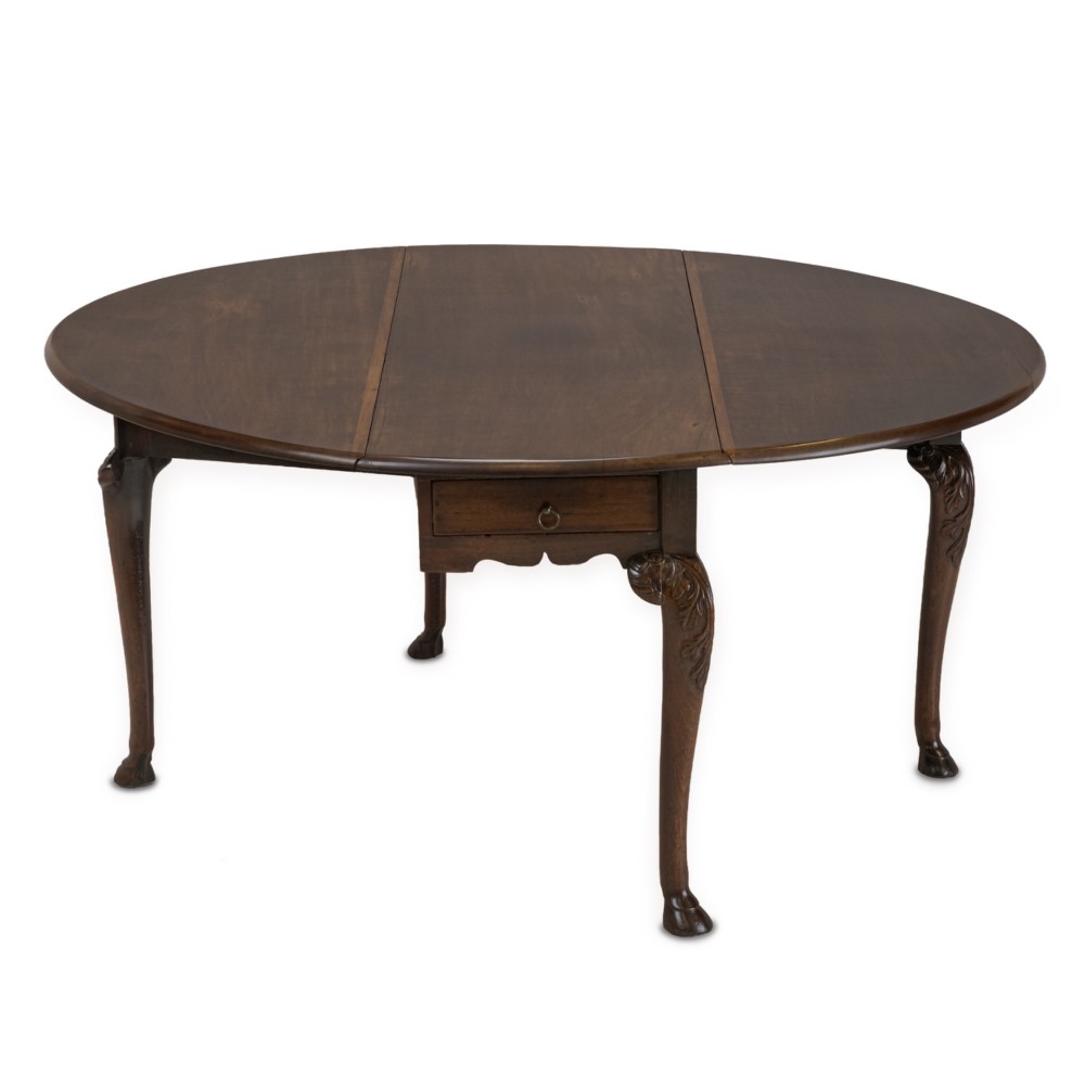 A George II Irish mahogany drop-leaf dining table with an oval top, end drawer, cabriole legs, and carved hoof feet.