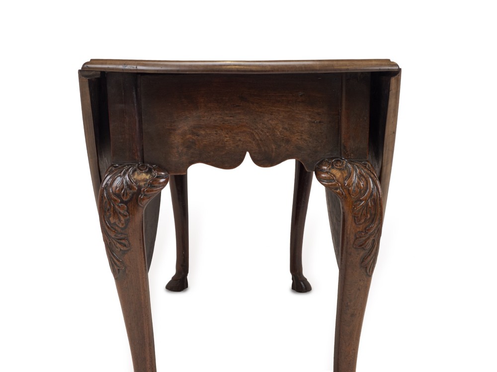 A George II Irish mahogany drop-leaf dining table with an oval top, end drawer, cabriole legs, and carved hoof feet. View X