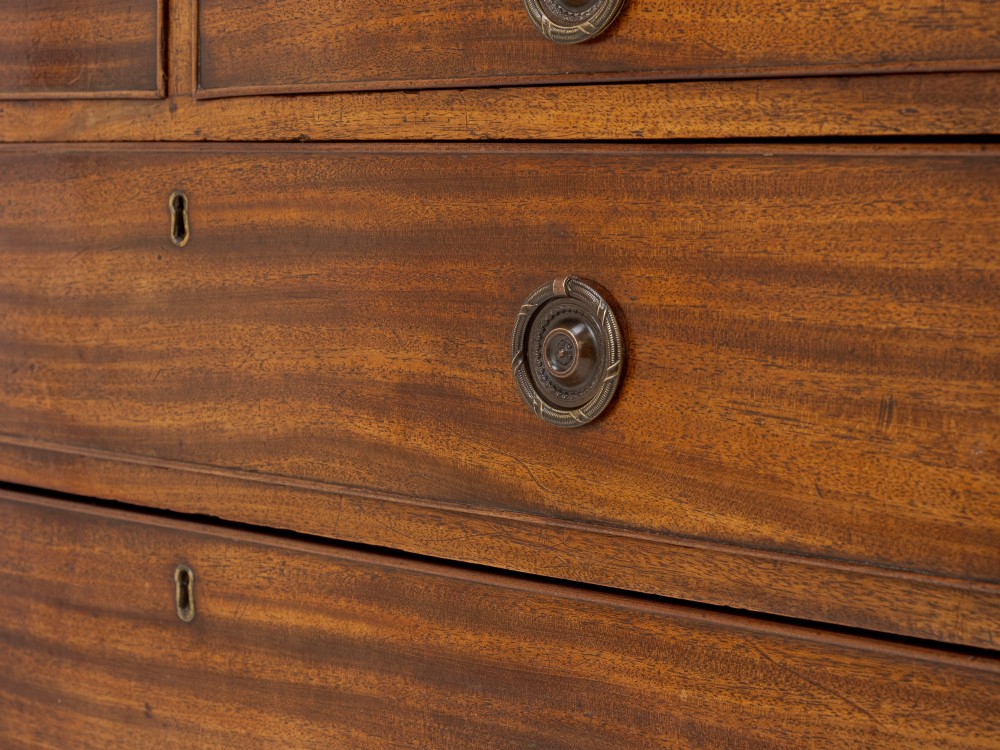 A late Georgian Regency mahogany chest of drawers featuring a caddy top, two short drawers over three long drawers, brass ring handles, and splayed bracket feet. View VI