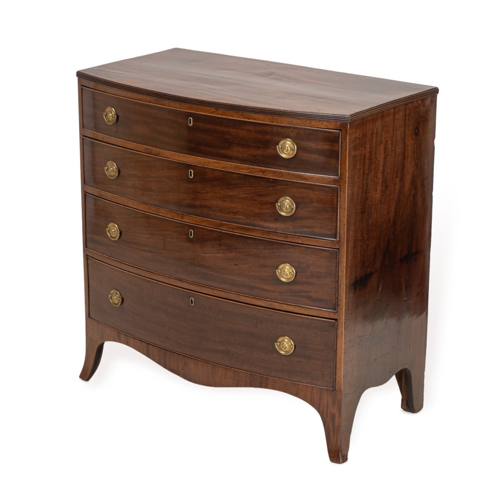 A Regency mahogany bow-front chest of drawers featuring four graduated drawers with circular brass ring handles and splayed bracket feet. View II