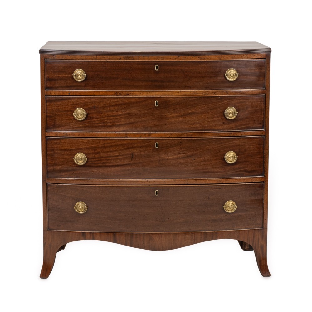 A Regency mahogany bow-front chest of drawers featuring four graduated drawers with circular brass ring handles and splayed bracket feet. View III