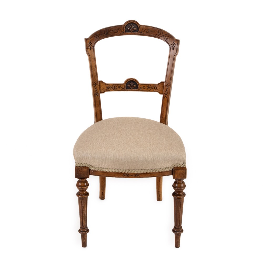 A set of four antique Regency satin birch dining chairs featuring carved crest rails, turned front legs, and neutral fabric upholstered seats. View III
