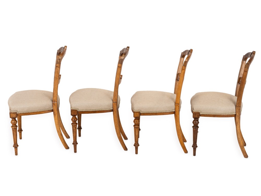 A set of four antique Regency satin birch dining chairs featuring carved crest rails, turned front legs, and neutral fabric upholstered seats. View X