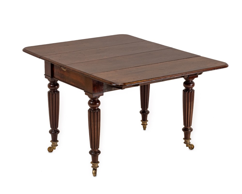 An extended Georgian mahogany dining table featuring a smooth polished surface, rectangular top with rounded corners, and reeded turned legs with brass castors. View III