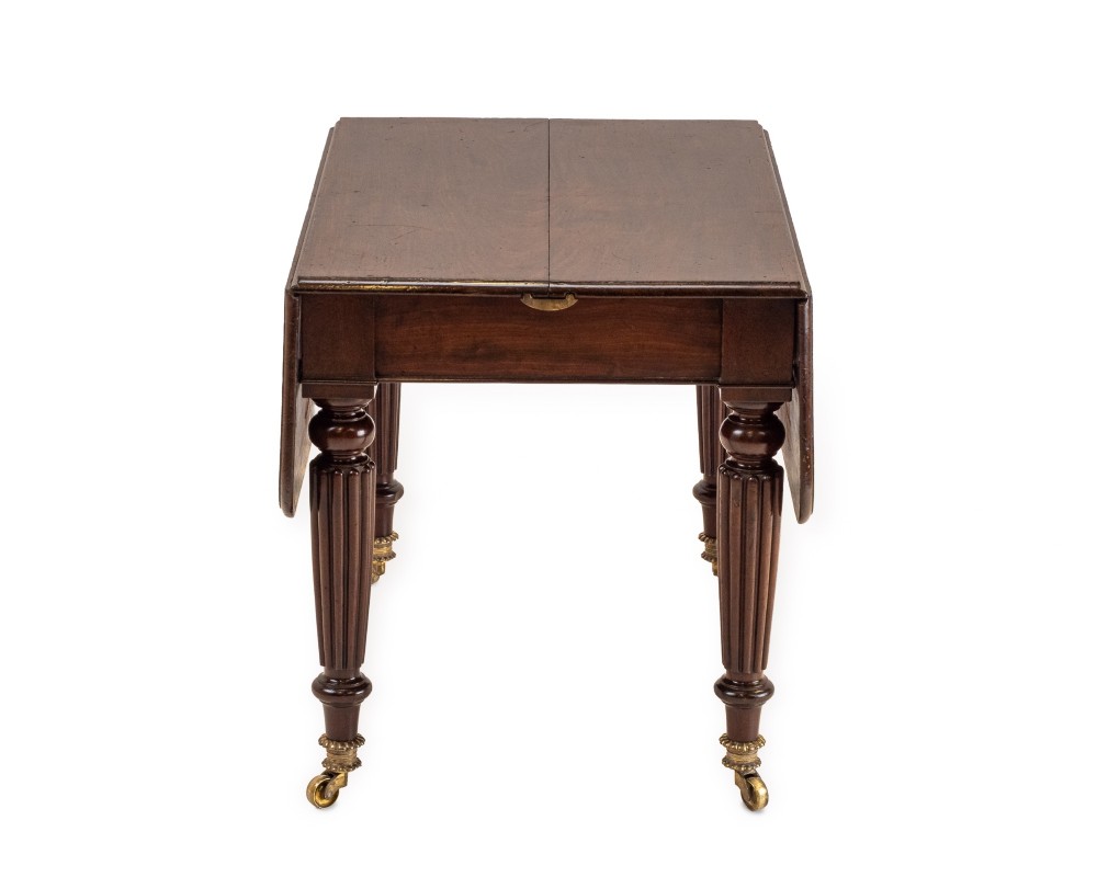 An extended Georgian mahogany dining table featuring a smooth polished surface, rectangular top with rounded corners, and reeded turned legs with brass castors. View VIII