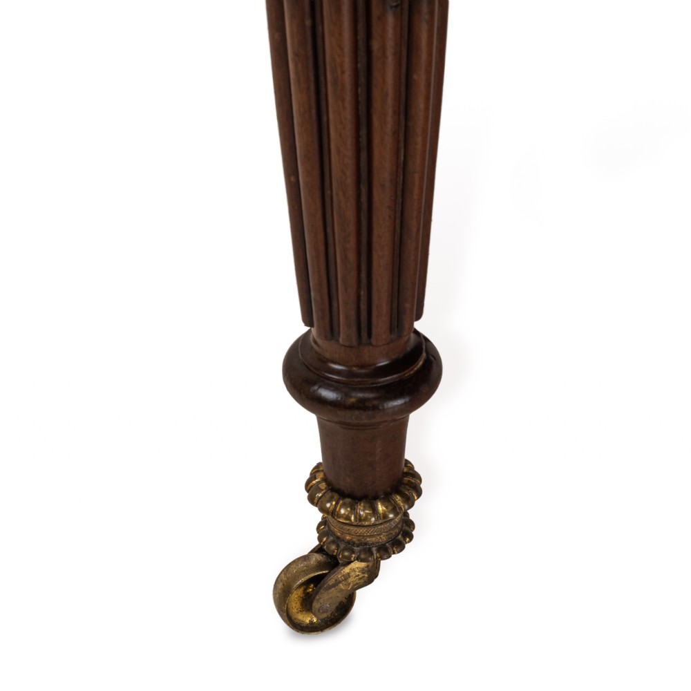 An extended Georgian mahogany dining table featuring a smooth polished surface, rectangular top with rounded corners, and reeded turned legs with brass castors. View IX