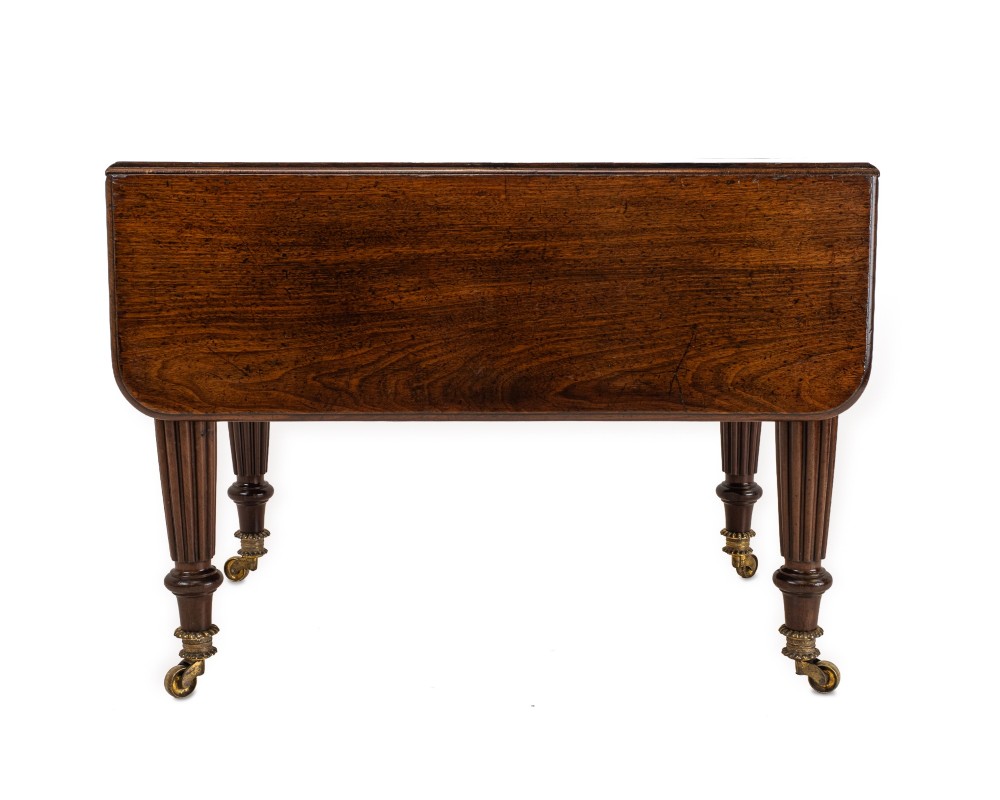 An extended Georgian mahogany dining table featuring a smooth polished surface, rectangular top with rounded corners, and reeded turned legs with brass castors. View XIV