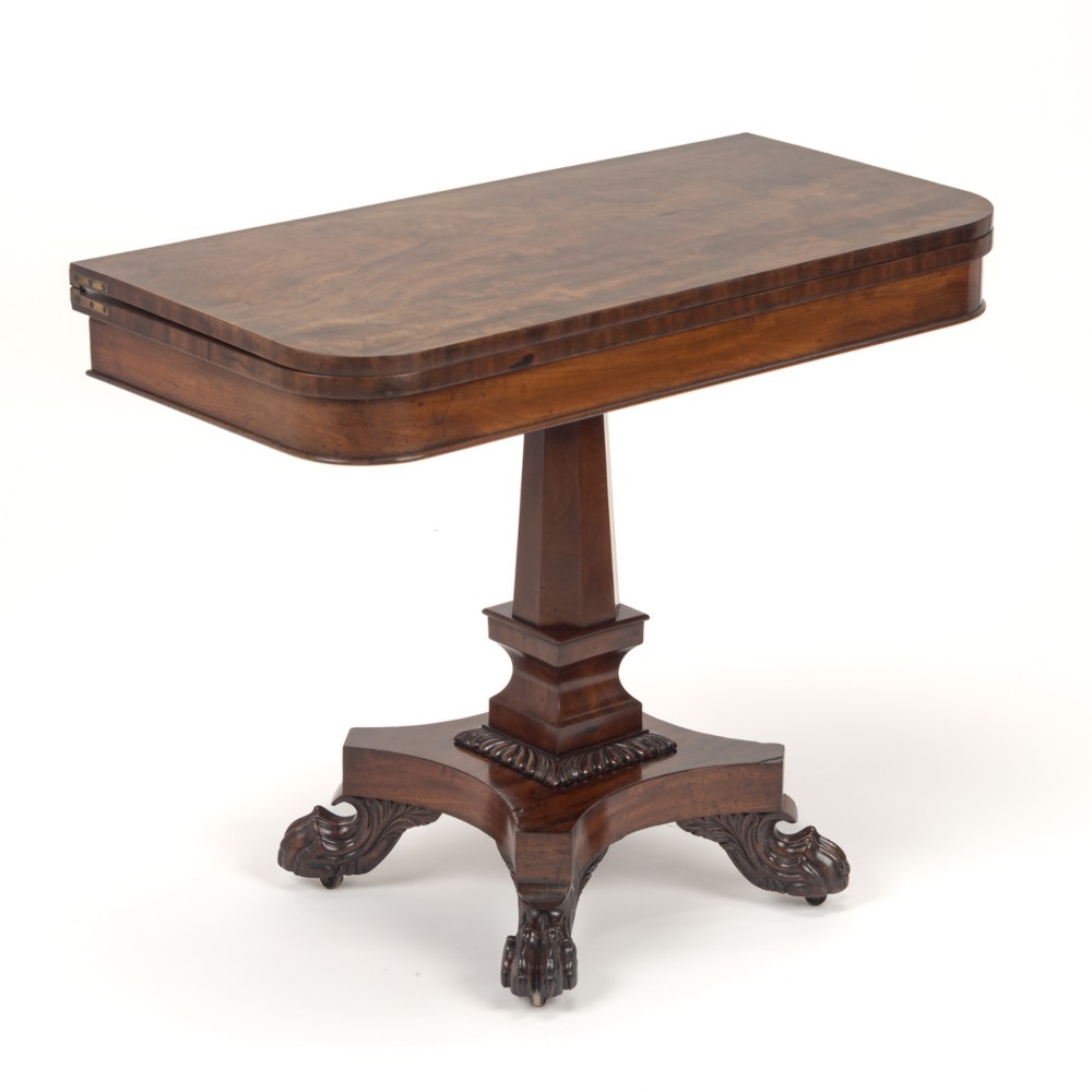 A late Regency mahogany fold-over tea table featuring a tapered central pedestal and carved paw feet on a concave quadform base. View II