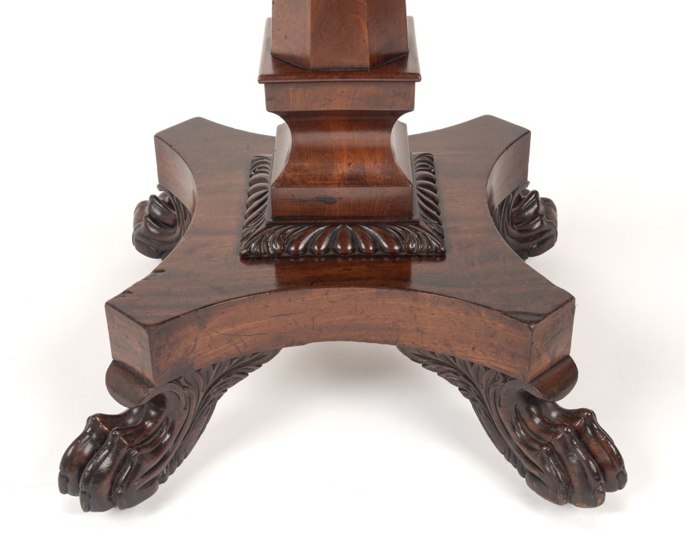 A late Regency mahogany fold-over tea table featuring a tapered central pedestal and carved paw feet on a concave quadform base. View V