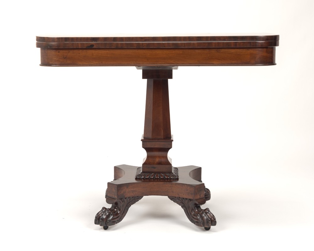 A late Regency mahogany fold-over tea table featuring a tapered central pedestal and carved paw feet on a concave quadform base. View VI