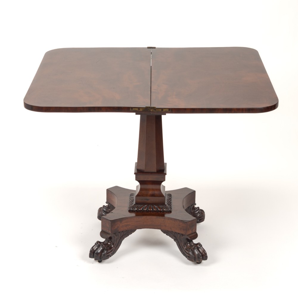 A late Regency mahogany fold-over tea table featuring a tapered central pedestal and carved paw feet on a concave quadform base. View VIII