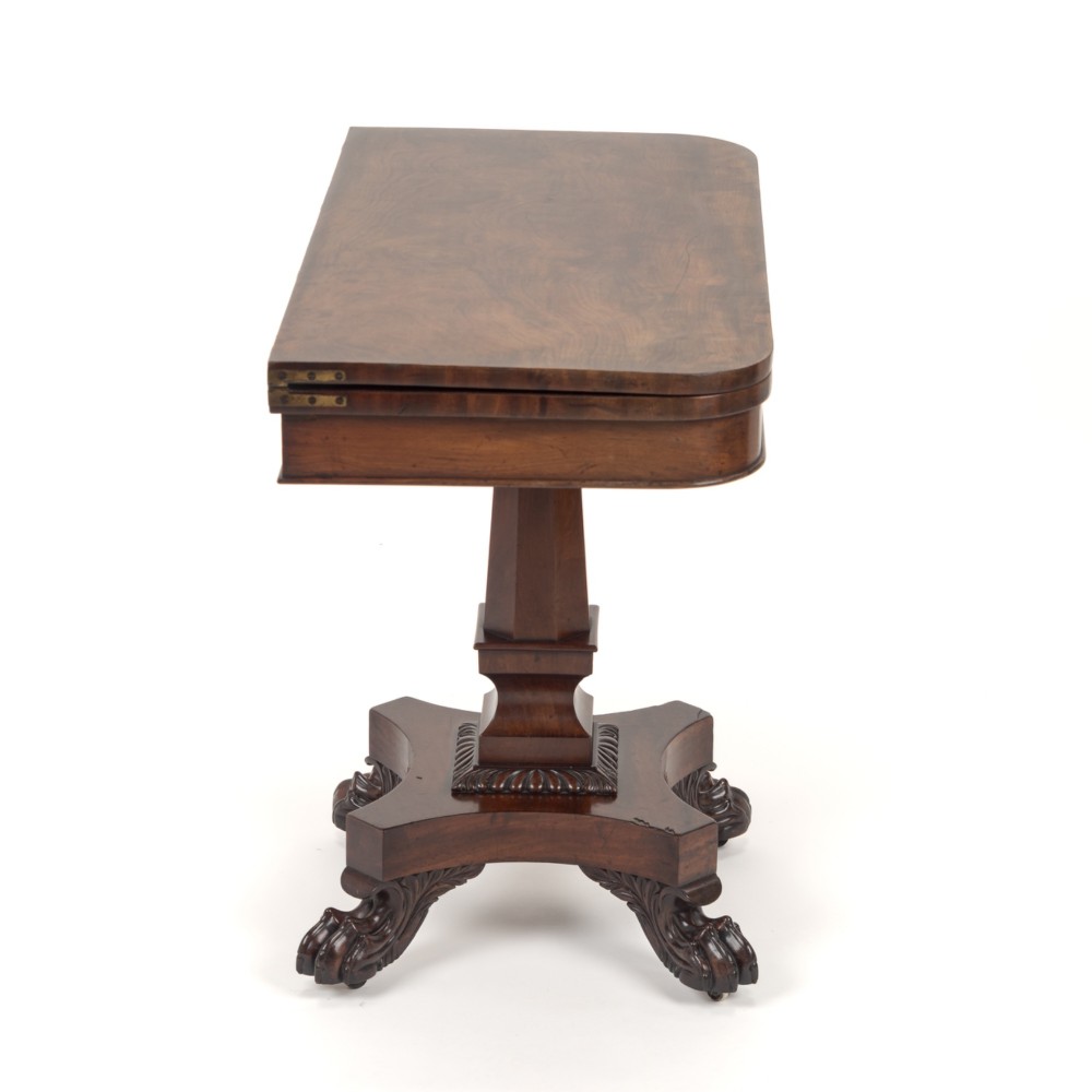 A late Regency mahogany fold-over tea table featuring a tapered central pedestal and carved paw feet on a concave quadform base. View IX