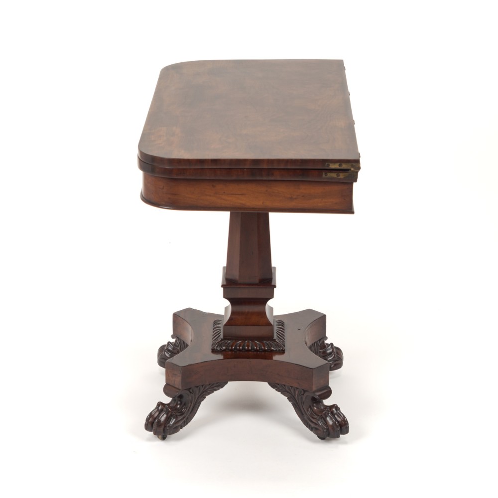 A late Regency mahogany fold-over tea table featuring a tapered central pedestal and carved paw feet on a concave quadform base. View X
