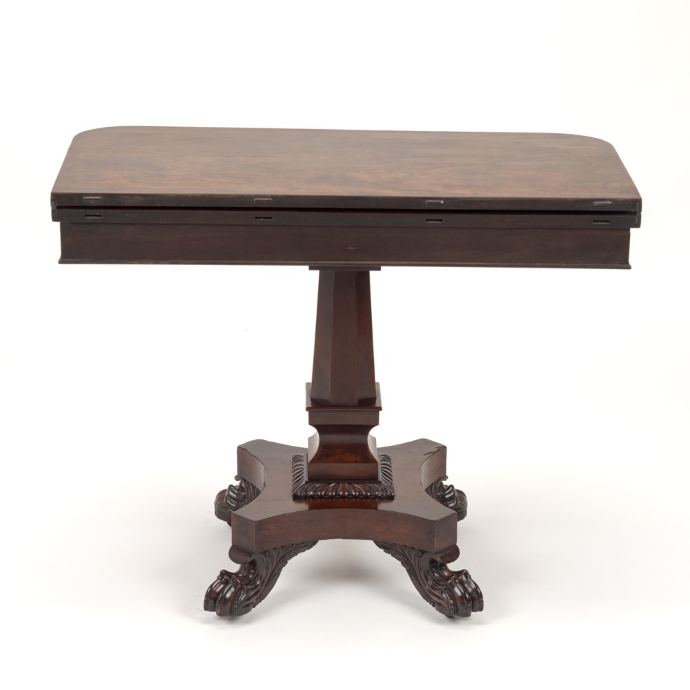 A late Regency mahogany fold-over tea table featuring a tapered central pedestal and carved paw feet on a concave quadform base. View XII