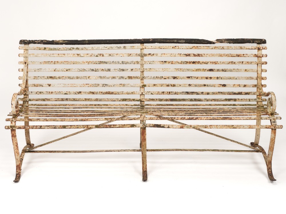 An early 19th-century Regency wrought iron garden bench featuring horizontal strapwork slats, scroll armrests, and a weathered paint finish. View II