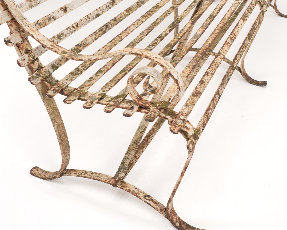 An early 19th-century Regency wrought iron garden bench featuring horizontal strapwork slats, scroll armrests, and a weathered paint finish. View VII