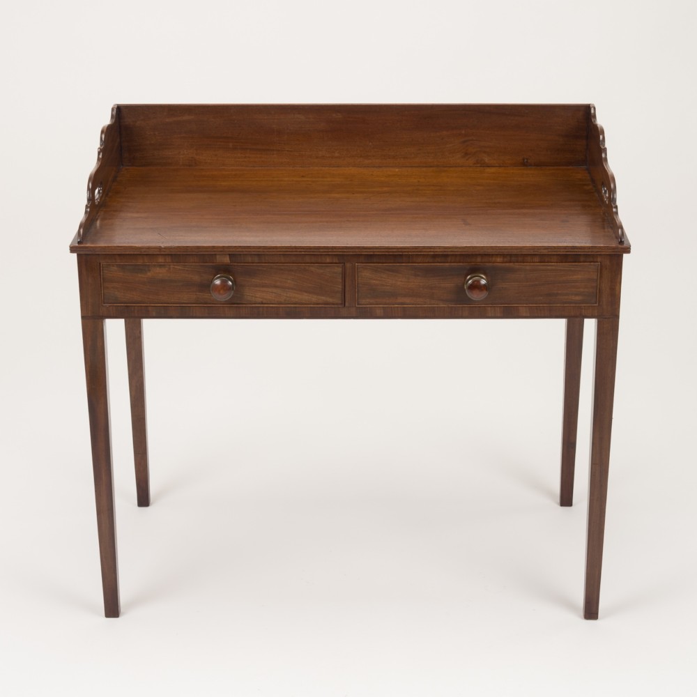 An early 19th-century mahogany tray-top writing table featuring a gallery edge with side cutout handles, two drawers with knob handles, and square tapered legs. View III