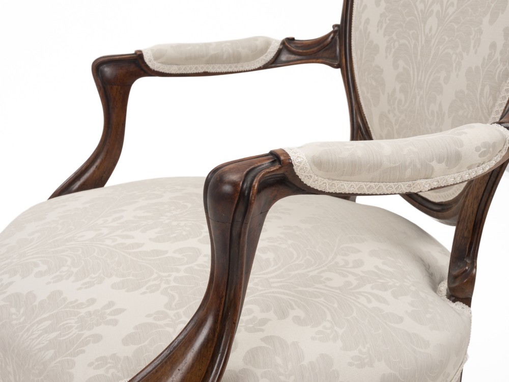 A pair of mid-19th century English rosewood Rococo Revival open armchairs with oval damask backs, carved top crests, padded arms, and cabriole legs on castors. View VI
