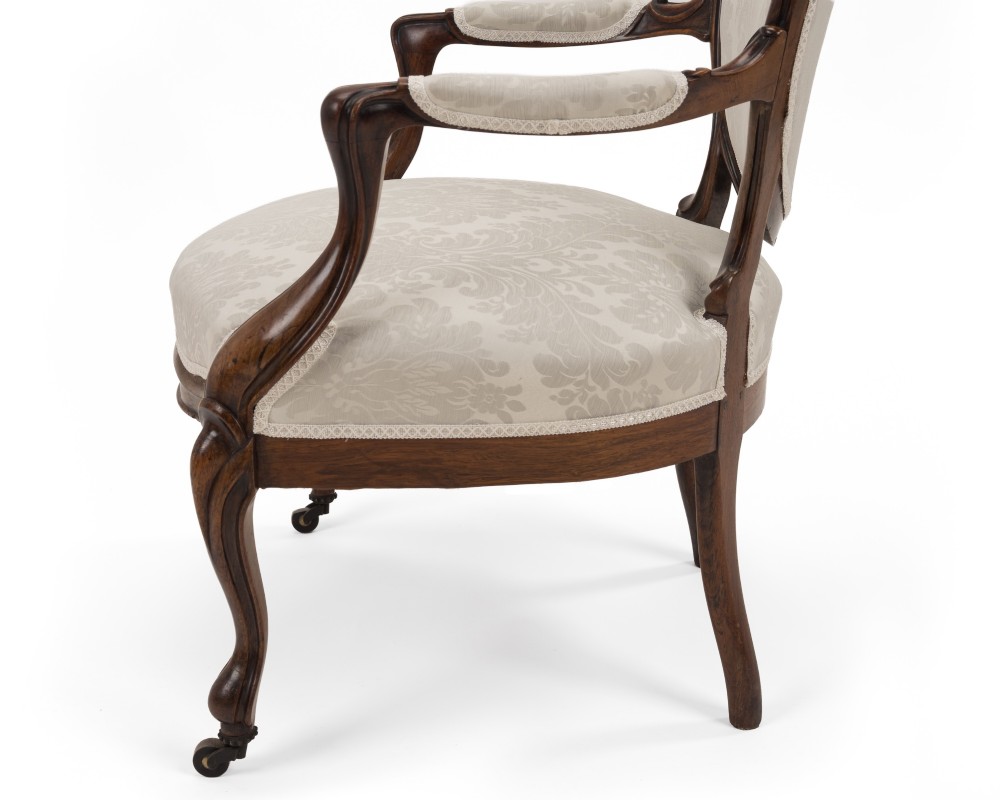 A pair of mid-19th century English rosewood Rococo Revival open armchairs with oval damask backs, carved top crests, padded arms, and cabriole legs on castors. View VIII