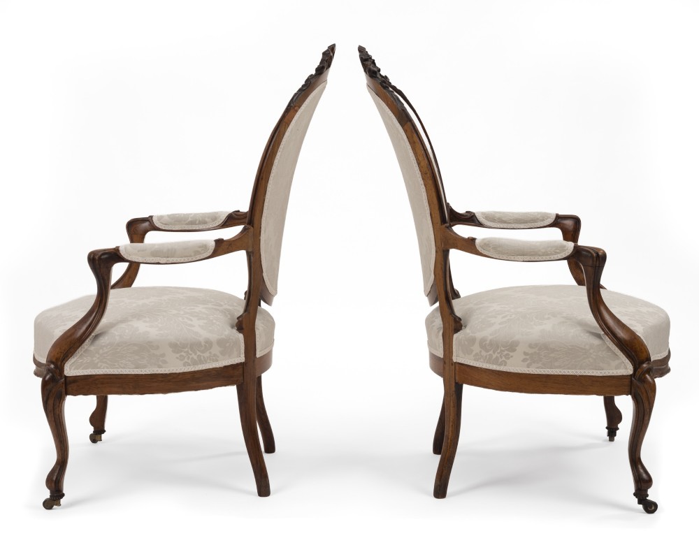 A pair of mid-19th century English rosewood Rococo Revival open armchairs with oval damask backs, carved top crests, padded arms, and cabriole legs on castors. View XI