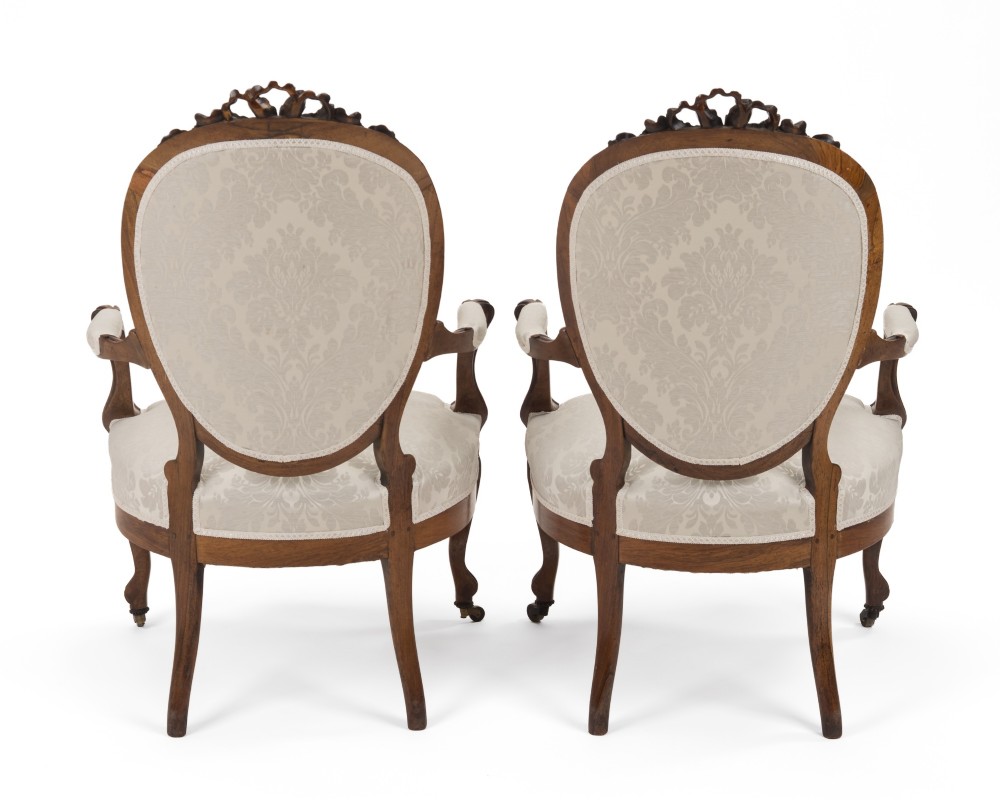 A pair of mid-19th century English rosewood Rococo Revival open armchairs with oval damask backs, carved top crests, padded arms, and cabriole legs on castors. View XII