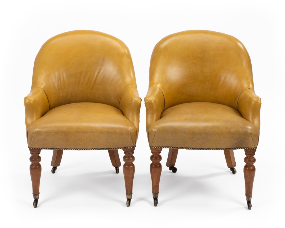 A pair of early 19th-century Regency library armchairs upholstered in warm tan leather with turned maple front legs on brass castors. View II