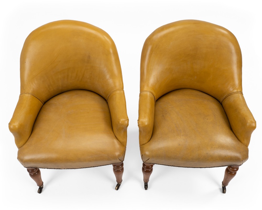 A pair of early 19th-century Regency library armchairs upholstered in warm tan leather with turned maple front legs on brass castors. View V