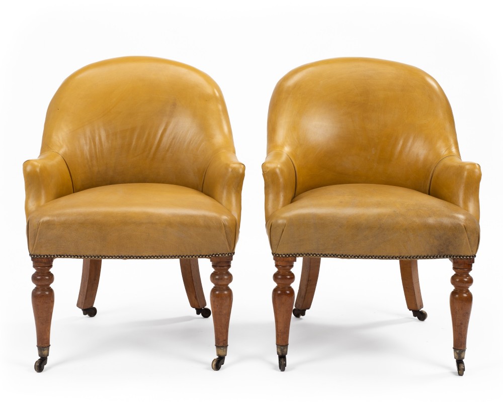 A pair of early 19th-century Regency library armchairs upholstered in warm tan leather with turned maple front legs on brass castors. View VI
