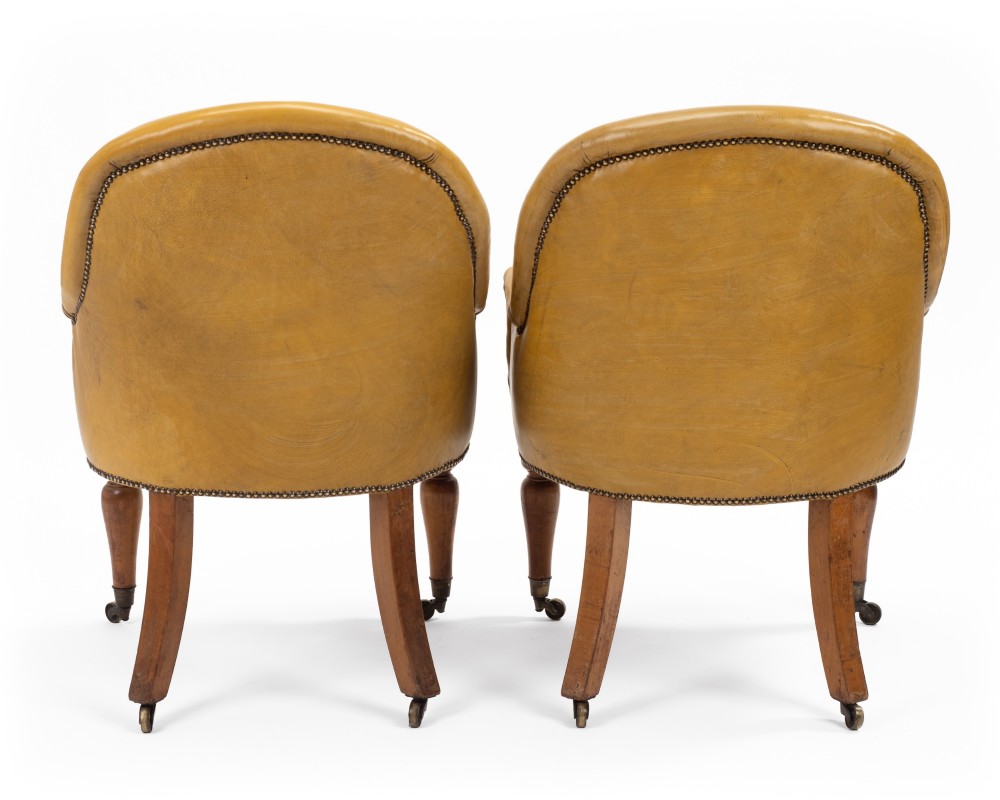 A pair of early 19th-century Regency library armchairs upholstered in warm tan leather with turned maple front legs on brass castors. View VII