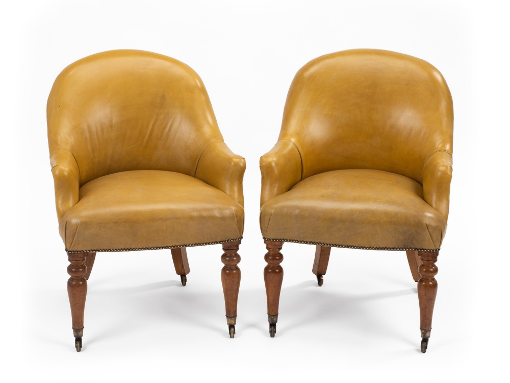 A pair of early 19th-century Regency library armchairs upholstered in warm tan leather with turned maple front legs on brass castors. View IX
