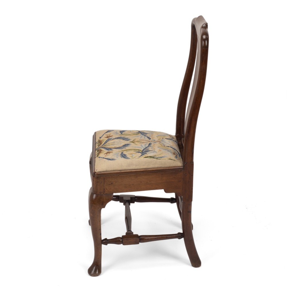 A George II walnut side chair featuring a shaped vasiform splat, cabriole front legs with pad feet, turned stretchers, and a floral needlework drop-in seat. View X